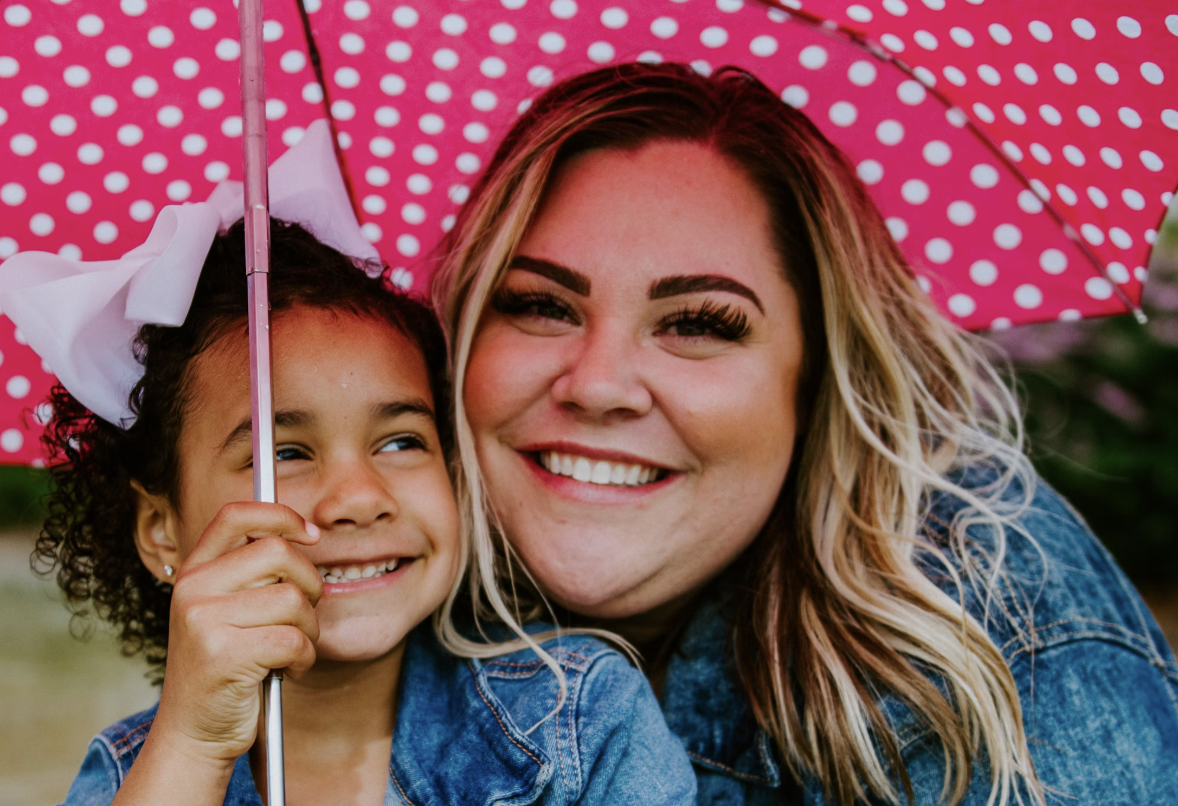 A woman and a little girl under an umbrella.