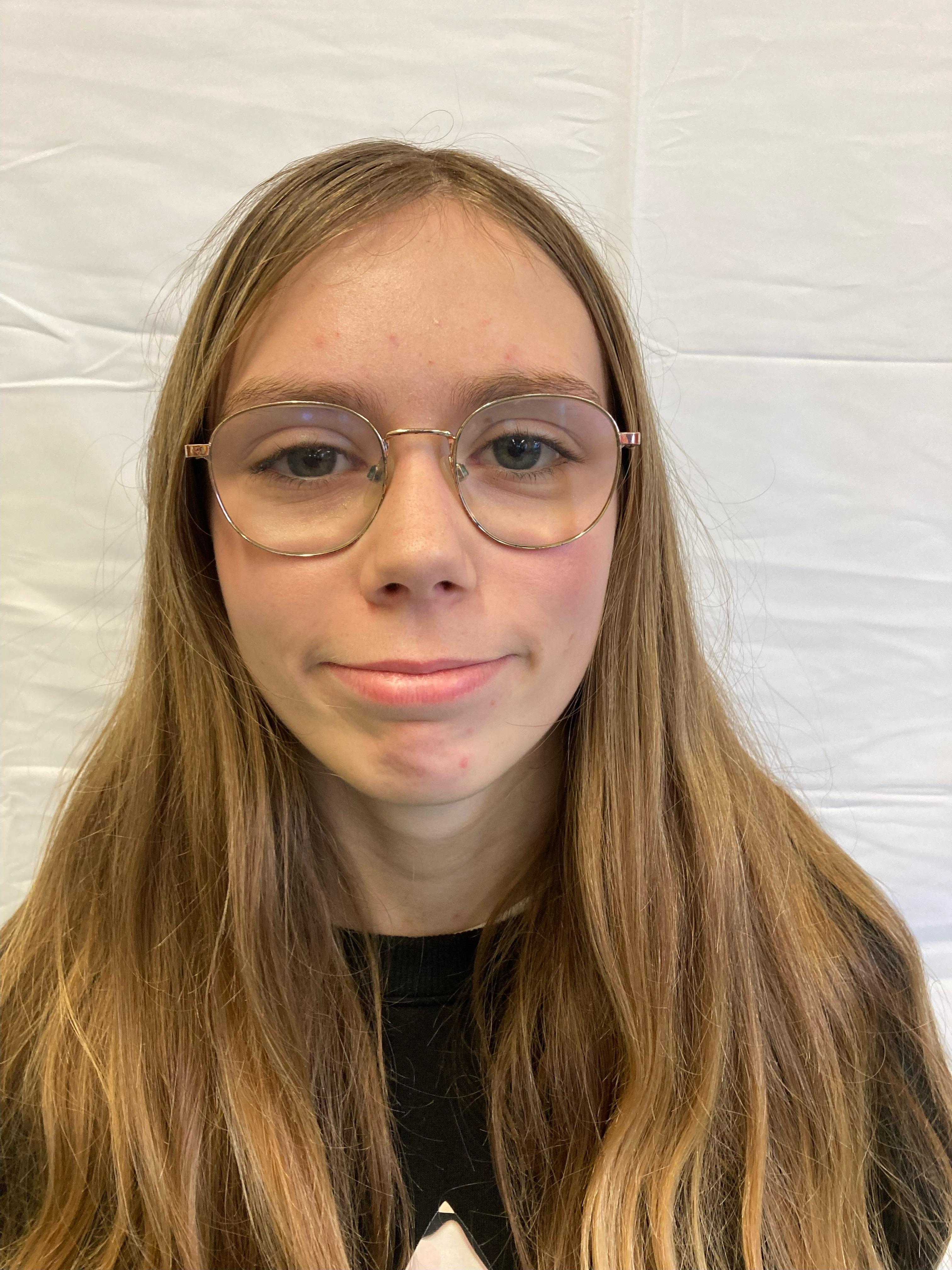 A girl with blonde hair and glasses poses for a profile picture.