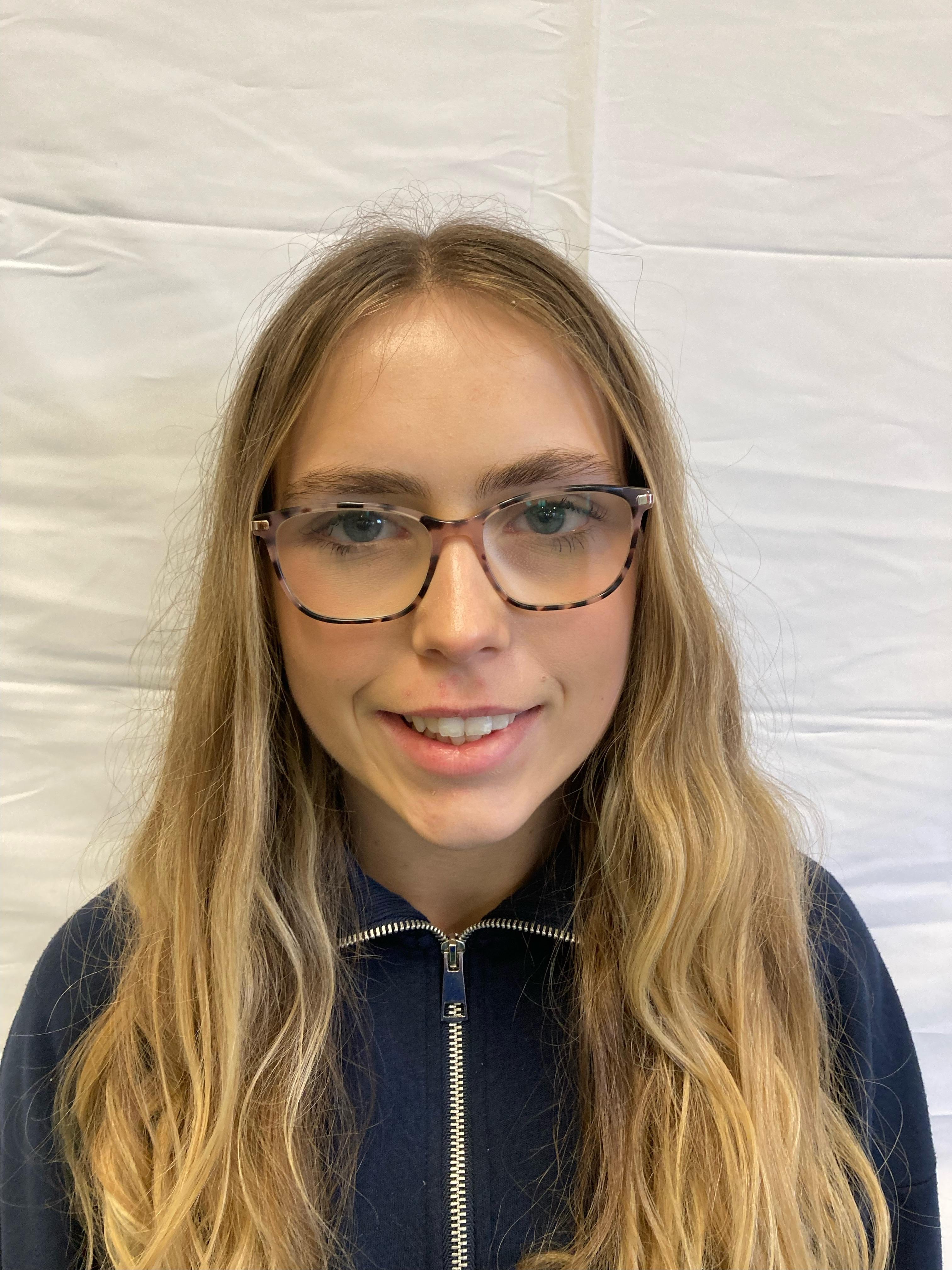 A girl with blonde hair and glasses poses for a profile picture.