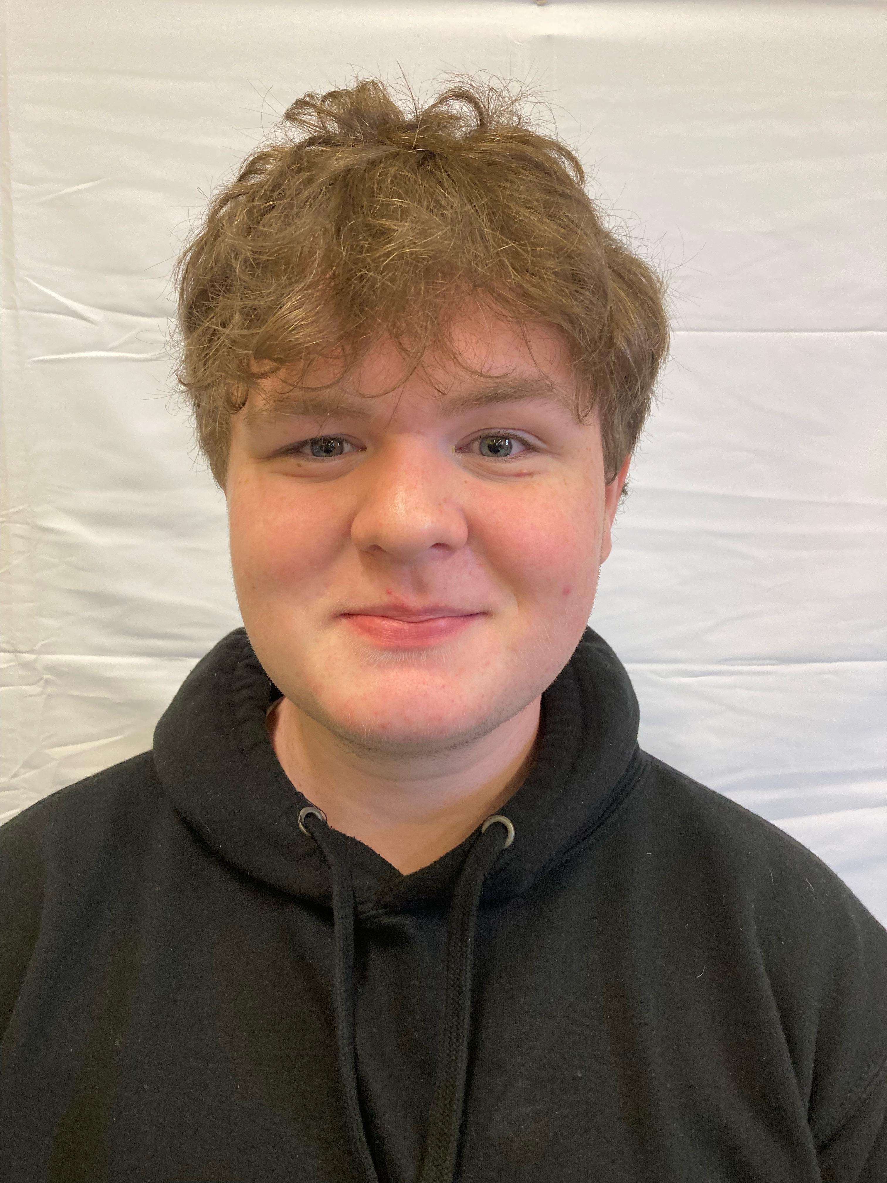 A boy with blonde hair wearing a black hoodie poses for a profile picture.