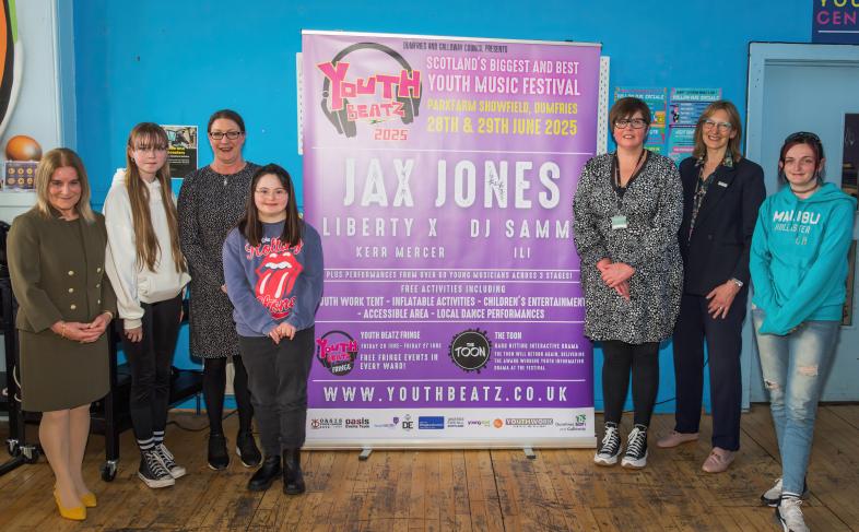 A group of people standing in front of a Youth Beats poster