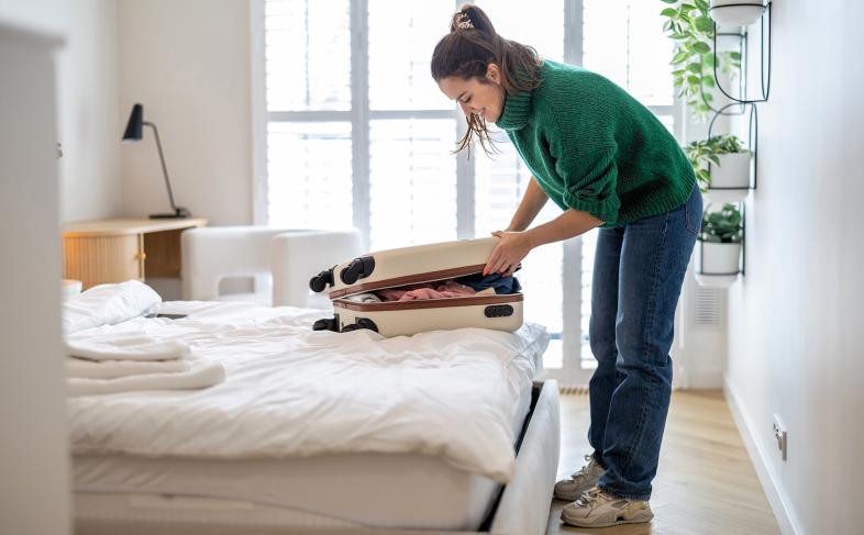 Person in a room packing a suitcase