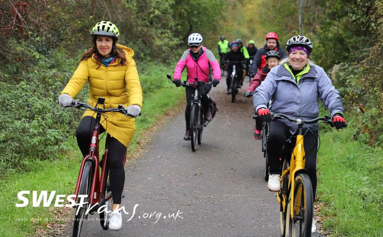 Group of people cycling together, smiling at the camera