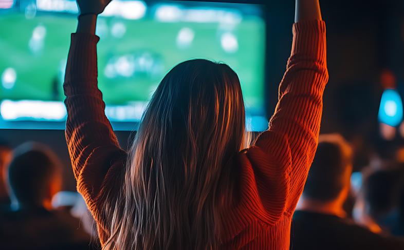 Person cheering at sports bar, watching game on TV with friends. Concept of sports, bar, fan, celebration, excitement.