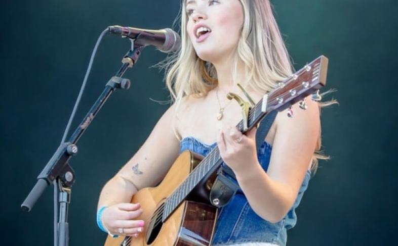 Young person playing acoustic guitar on stage