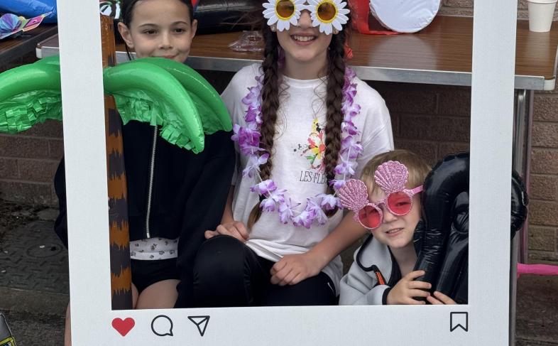 Three young people posing inside a giant Instagram photo frame prop at a youth event in Dumfries and Galloway