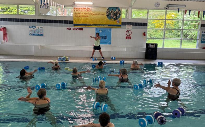 people in a swimming pool using weights in an aqua aerobics class