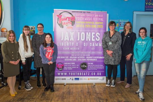 A group of people standing in front of a Youth Beats poster
