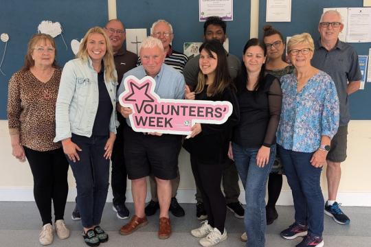 Volunteer adult support tutors hold up a Volunteers' Week sign.