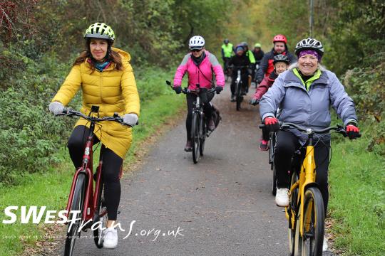 Group of people cycling together, smiling at the camera