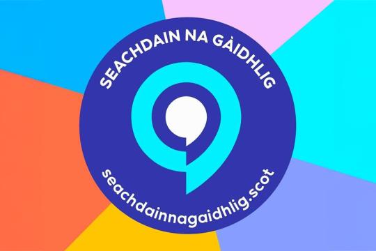 A colourful logo with a circular design in blue, featuring white text "Seachdain na Gàidhlig" and a speech bubble. Background has pastel colour segments.