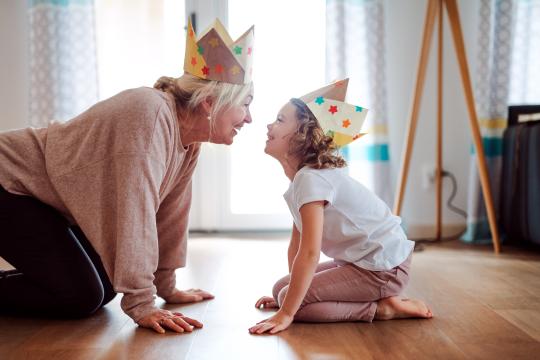 A grandmother and grand-daughter play together wearing paper crowns. 