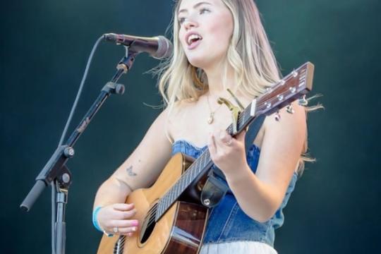 Young person playing acoustic guitar on stage