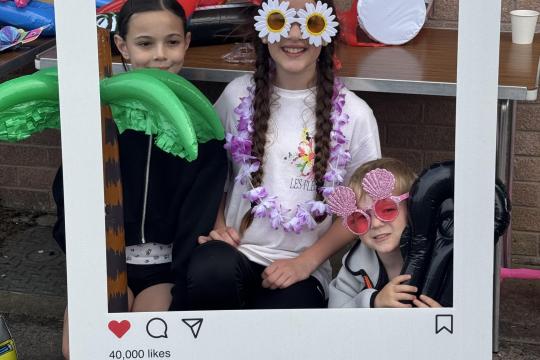 Three young people posing inside a giant Instagram photo frame prop at a youth event in Dumfries and Galloway