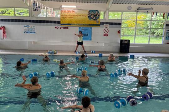 people in a swimming pool using weights in an aqua aerobics class